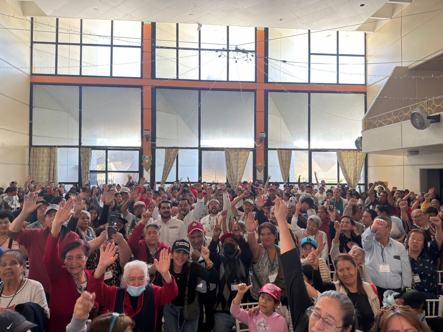 Ciudadanía participando en asamblea con manos levantadas